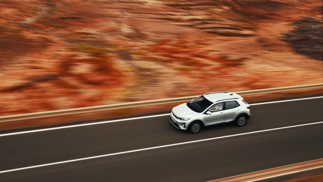 White SUV on a road cut through red volcanic rock