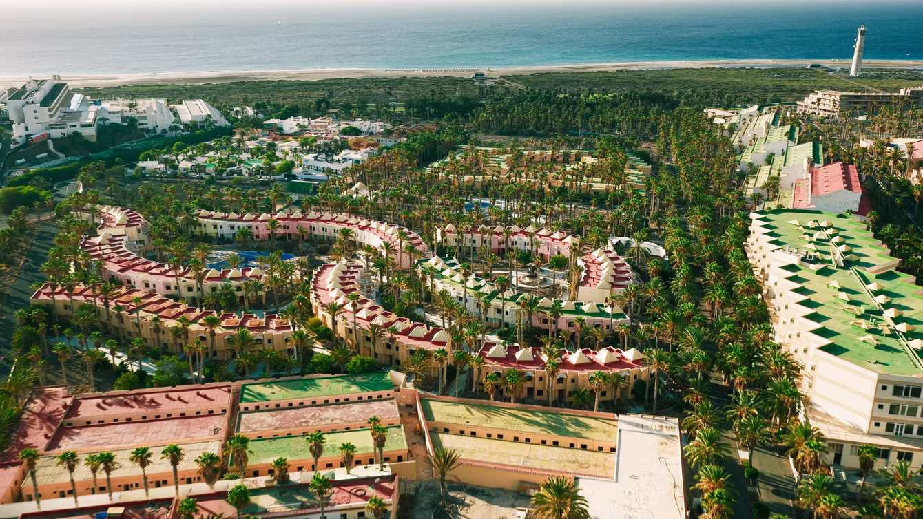 Aerial view of a bungalow resort with lawns and pools