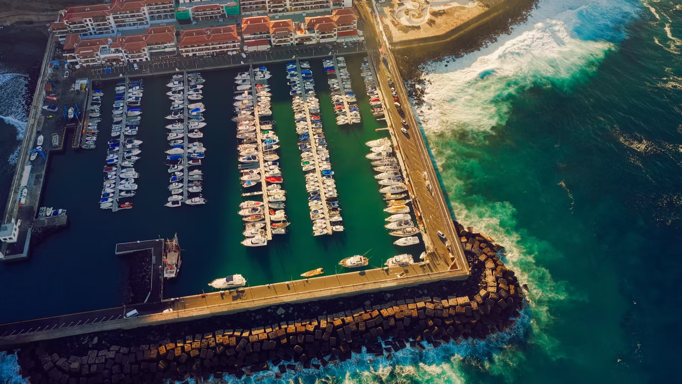Marina full of yachts behind a breakwater, seen from above
