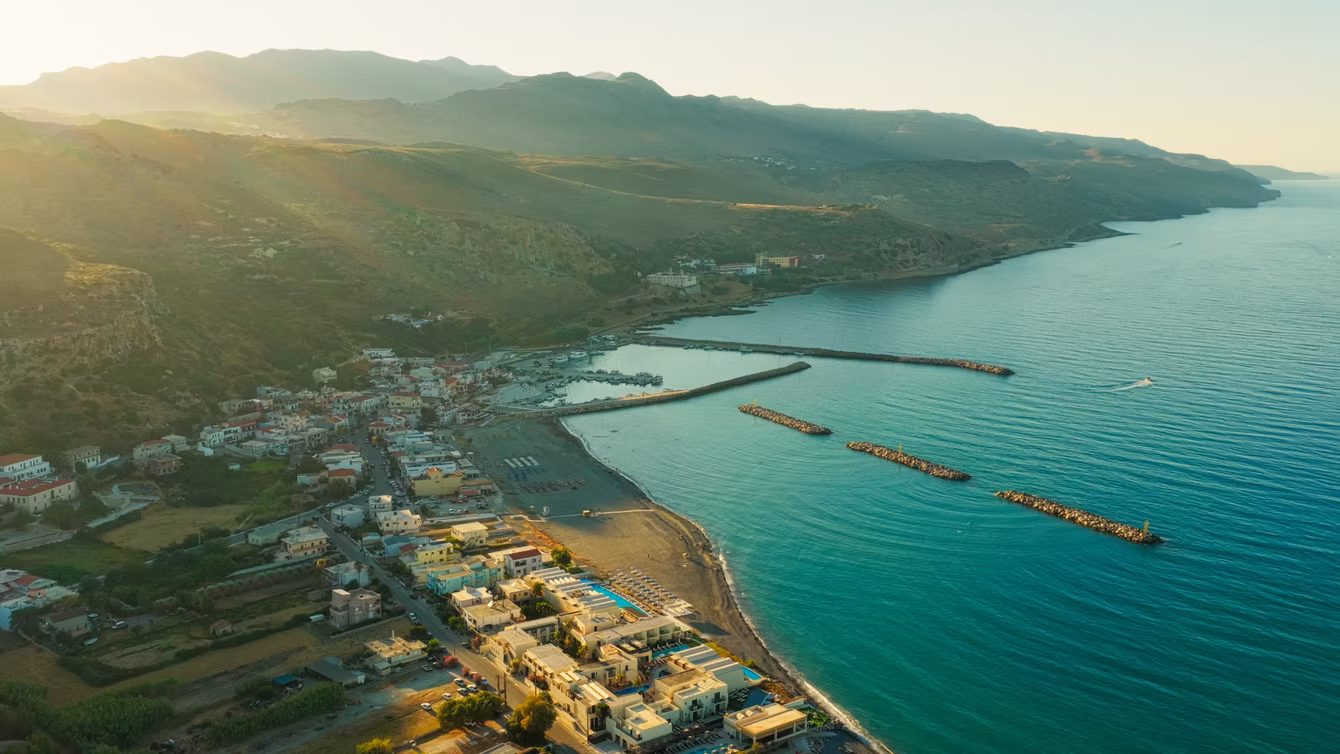 Aerial view of a sheltered bay with a pier and coastal village
