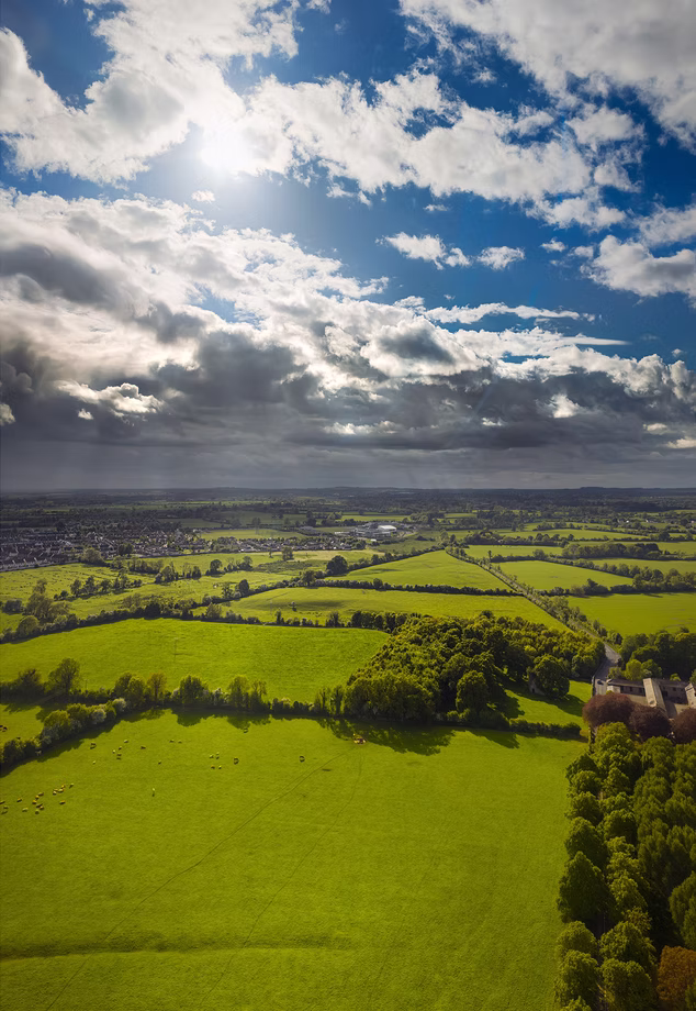 Green Irish fields and hedgerows under a broken sky
