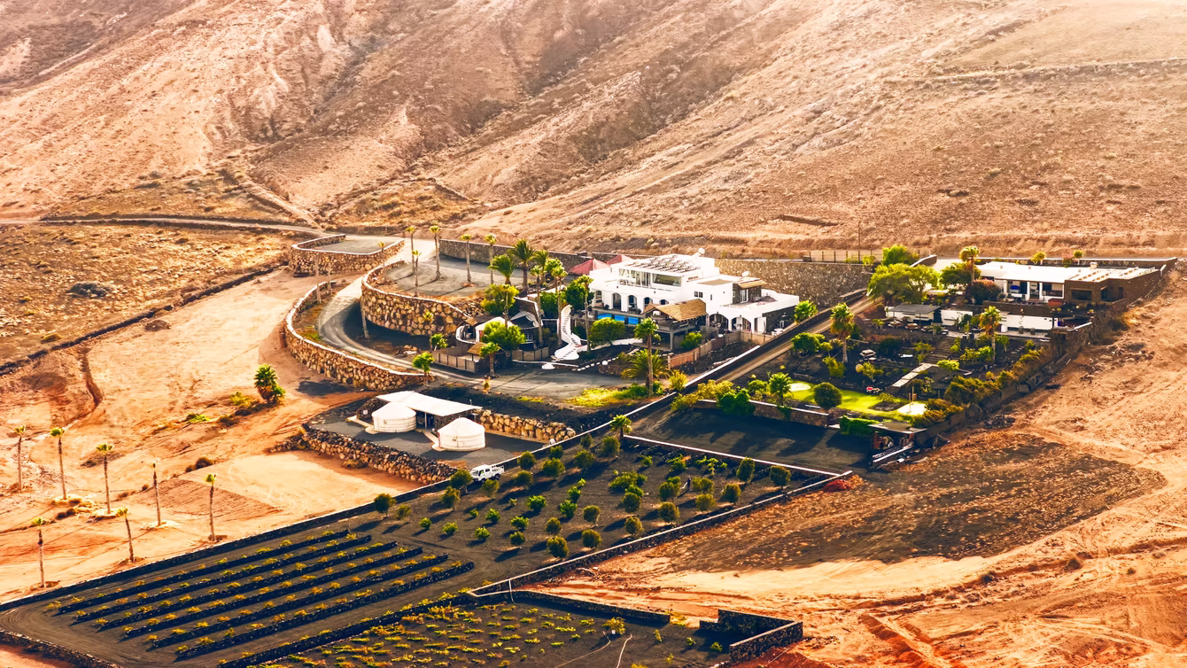 White estate house on arid volcanic land, shot from the air